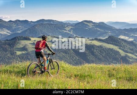 Hübsche ältere Frau auf ihrem elektrischen Mountainbike auf den Bergen oberhalb Oberstaufen, Allgauer Alpen, Bayern Deutschland Stockfoto