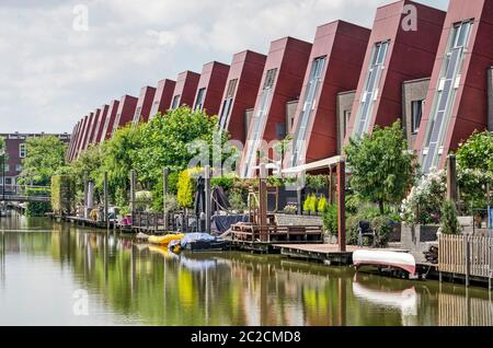 Den Haag, Niederlande, 13. Juni 2020: Leicht geschwungene Häuserzeile mit Solarzellen und Gärten mit Anlegesteg am Kanal in Wateringseveld ne Stockfoto