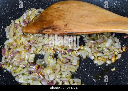 Kochen gehackte rote Zwiebeln mit Olivenöl auf einer Pfanne aus nächster Nähe. Stockfoto