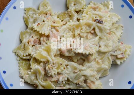 Farfalle Pasta mit geräuchertem Lachs und roten Zwiebeln in einer Sahnesauce. Nahaufnahme von oben. Stockfoto