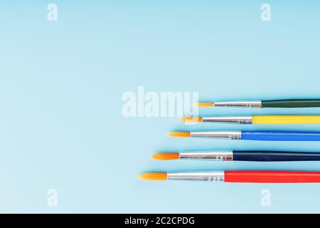 Pinsel in verschiedenen Farben für Zeichnung, Kreativität und Kunst auf blauem Hintergrund. Stockfoto