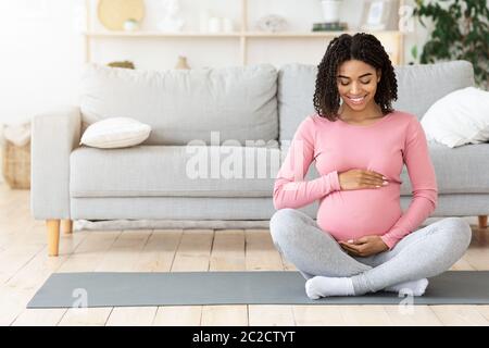 Glücklich schwangere schwarze Frau berühren ihren Bauch Stockfoto