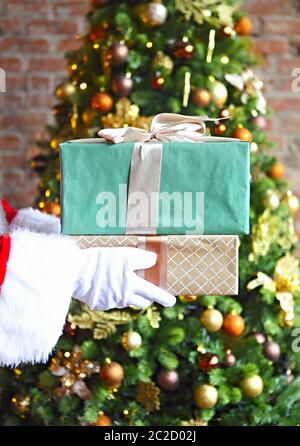 Der Weihnachtsmann stellt heimlich Geschenkschachteln am Weihnachtsbaum Stockfoto