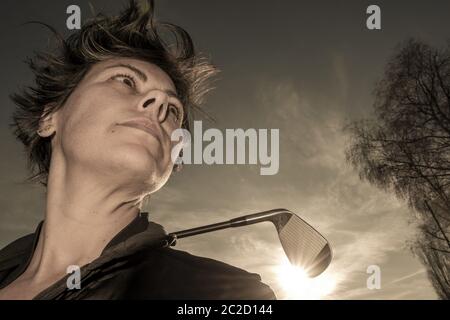 Golfer Leaning ihren Golfclub auf ihren Schultern mit Sonnenlicht. Stockfoto