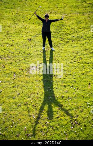 Luftaufnahme eines Golfers mit Erfolg Halten von Golfclub und Ball und Stehen auf dem Fairway mit Schatten. Stockfoto