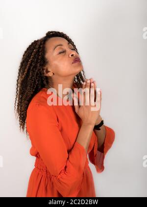 Vertikales Porträt einer afroamerikanischen Frau, die mit geschlossenen Augen betet Stockfoto