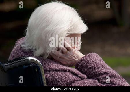 Unglückliche ältere Dame, die im Rollstuhl halb schläft Stockfoto