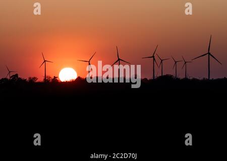 Schwarze Silhouette von Windenergieanlagen Energie generator auf eine erstaunliche Sonnenuntergang an einem Windpark in Deutschland Stockfoto