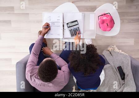 Junges Paar auf Sofa Berechnung Rechnungen zu Hause sitzen Stockfoto