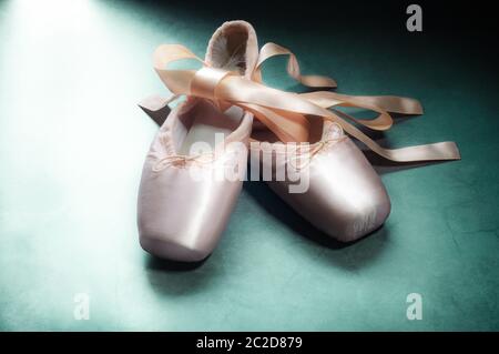 Pointe Shoes Ballet dance Schuhe mit einem Bogen der Bänder wunderschön auf einem grünen Hintergrund gefaltet Stockfoto