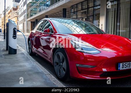 LONDON, JUNI 2020: Ein roter Tesla Model 3 parkte und lad auf der City Street Stockfoto