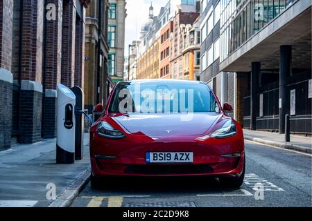 LONDON, JUNI 2020: Ein roter Tesla Model 3 parkte und lad auf der City Street Stockfoto