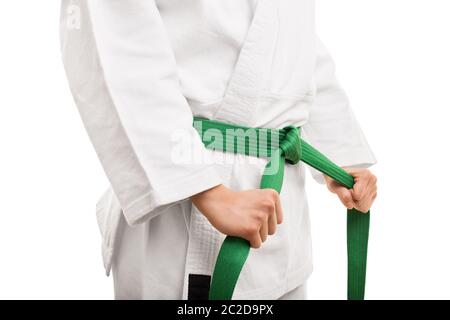 Vorbereitung für das Training. Nahaufnahme von den mittleren Abschnitt eines Mädchens im Kimono und band ihre Green Belt, auf weißem Hintergrund. Stockfoto