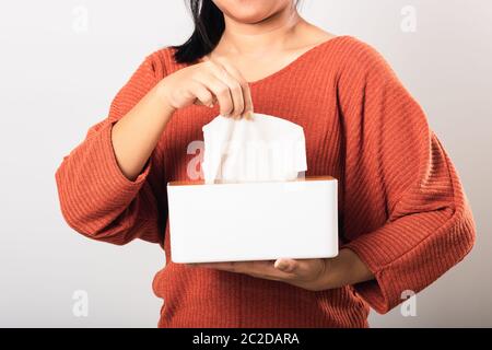 Junge Frau Grippe sie mit Hand, die weißes Gesichtstuch aus einer weißen Box für sauberes Taschentuch herausziehen, Studio auf weißem Hintergrund isoliert Stockfoto