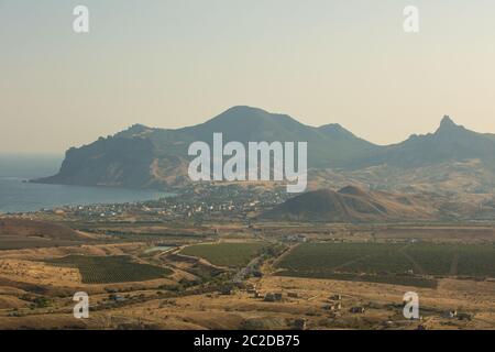 Panoramablick auf die Berge, die Landschaft, das Meer und das Dorf von dem Berg an einem sonnigen Sommertag. Russland, Krim Stockfoto