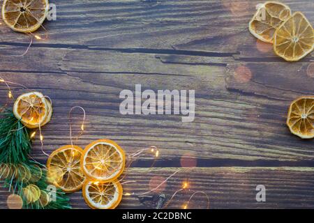 Weihnachtshintergrund aus getrockneten Orangen, Kiefernzweig und Girlande auf einem Holztisch. Draufsicht. Copyspace Stockfoto