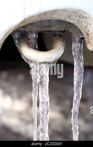 Viele große und scharfe Eiszapfen hängen am Auto. Stockfoto