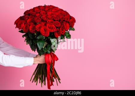 Foto von abgeschnitten Mann Arme halten große hundert rote helle Rosen Bündel geben Freundin Überraschung versteckt Gesicht geheimen Bewunderer Arrangement Lieferung Stockfoto