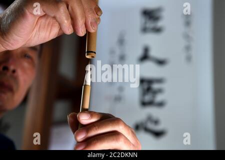 (200617) -- JINGXIAN, 17. Juni 2020 (Xinhua) -- She Zhengjun, eine Erbin der traditionellen Technik der Herstellung von Xuan-Bürsten, zeigt einen Xuan-Pinsel, den er in einer Werkstatt im Bezirk Jingxian, ostchinesische Provinz Anhui, am 5. Juni 2020 macht. Tintenpinsel werden in der traditionellen chinesischen Malerei und Kalligraphie verwendet. Zusammen mit Tintenstein, Tintenstift und Xuan-Papier bilden diese vier Schreibgeräte die "vier Schätze des Studiums". Die Xuan-Bürste ist eine hoch gelobte Art von Tintenpinsel, die vermutlich aus der Qin-Dynastie (um 200 v. Chr.) im Gebiet Xuanzhou im alten China stammt. Das Haar der Xuan Bürste ist Stockfoto