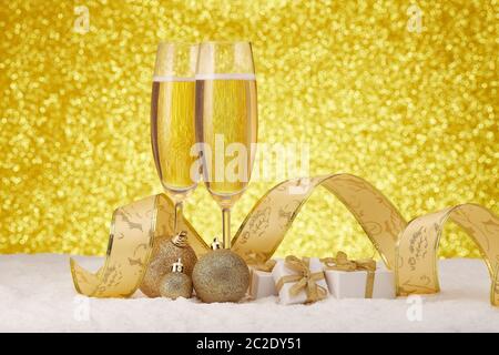 Zwei Weingläser mit Champagner, Geschenkboxen und Weihnachtsdekorationen stehen auf verschneiten Flächen auf festlichem Goldgrund. Kopierbereich. Weihnachten und Stockfoto