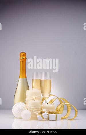 Weihnachten und Neujahr Stillleben mit zwei Weingläser Champagner, Flasche, Geschenkboxen und Weihnachtsschmuck auf einem grauen Hintergrund isoliert. Christus Stockfoto