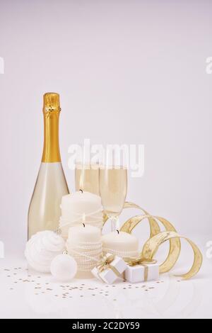 Weihnachten und Neujahr Stillleben mit zwei Weingläser Champagner, Flasche, Geschenkboxen und Weihnachtsschmuck auf weißem Hintergrund isoliert. Chris Stockfoto