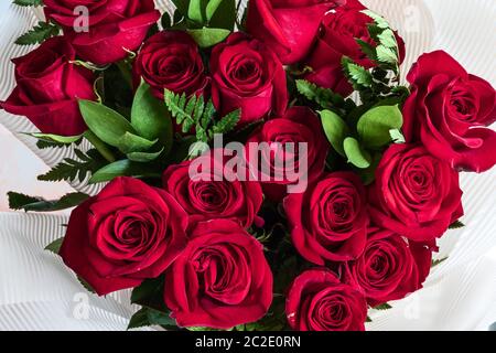 Ein schöner Strauß Rosen mit Elementen aus grünen Farnblättern aus der Nähe, Blick von oben. Stockfoto