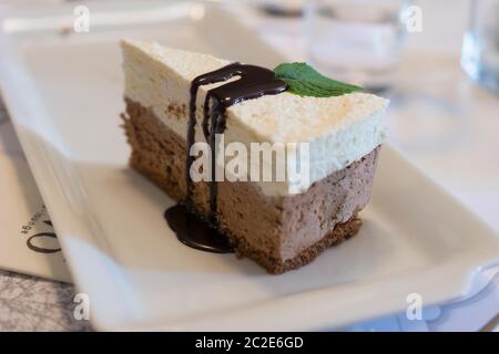 Scheibe von köstlichem Schokoladenmousse mit weißer und schwarzer Schokolade, Biskuitkuchen und dunkler Schokoladenglasur Belag Stockfoto