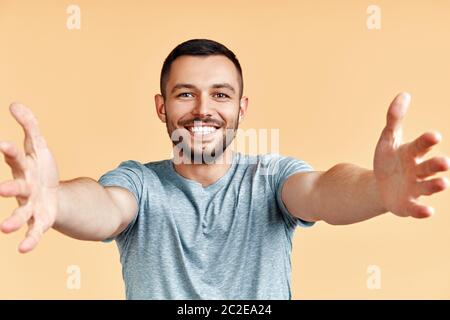 Schöner glücklicher Mann mit offener Hand bereit für Umarmungen auf gelbem Hintergrund Stockfoto