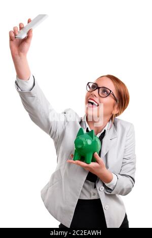 Lächelnd schöne junge geschäftsfrau in einem Anzug mit Brille ein selfie mit einem grünen Sparschwein gekleidet, auf einem weißen Hintergrund. Stockfoto