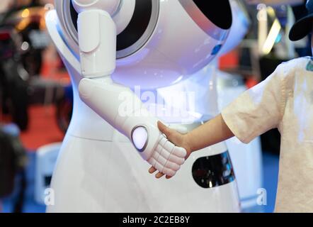 Freundlicher Roboter schüttelt die Hände mit kleinen Jungen, Technologie Smart Roboter Konzept Stockfoto