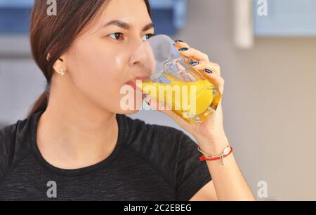 Porträt einer jungen asiatischen Frau in einem schwarzen T-Shirt bereitet das Frühstück und Getränke frisch gepressten Orangensaft in der Küche. Clouse Foto Stockfoto