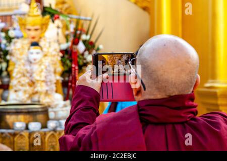 Ein buddhistischer Mönch, der ein Foto in der Shwedagon Pagode, Yangon, Myanmar macht. Stockfoto