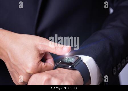 Geschäftsmann Scannen Fingerabdruck auf Smart Watch für den Zugriff auf sein anderes Gerät, zukünftige Technologie-Konzept Stockfoto