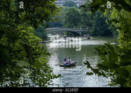 Rudern eines Bootes am Central Park See, mitten in Bäumen und Gebäuden als Hintergrund. Stockfoto