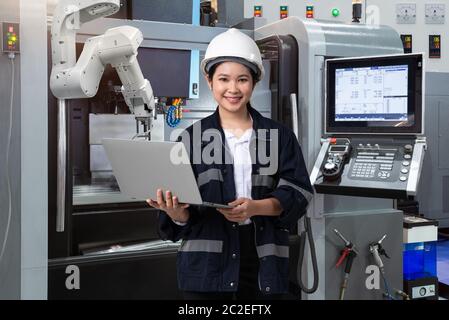Wartung weibliche Ingenieur mit Laptop-Computer-Steuerung automatische Roboterhand mit CNC-Maschine in Smart Factory, Industrie 4.0 Konzept Stockfoto