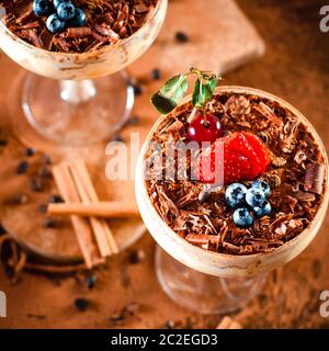 italienisches Dessert Tiramisu mit Erdbeere in einem eleganten Cocktailglas, das Konzept des süßen Lebens, Luxus Stockfoto