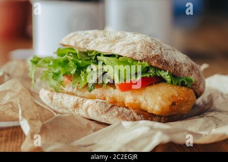 Gebratener Fisch auf einem Brötchen mit Salat, Tomate Street Food Stockfoto