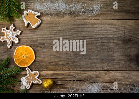 Weihnachtshintergrund aus alten Holzbrettern mit Platz für Kopierraum, Plätzchen in Form von Engeln und Schneeflocken, eine orangefarbene Scheibe, eine goldene Nuss Stockfoto