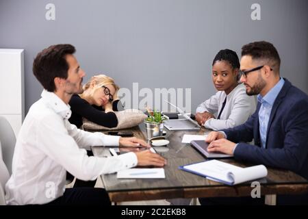 Müde Geschäftsfrau Schlafen beim Sitzen am Schreibtisch mit Ihren Kollegen Stockfoto