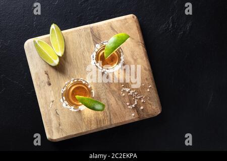 Golden tequila Schüsse mit Salz und Limette, Scheiben, geschossen von oben auf einem schwarzen Hintergrund mit Kopie Raum Stockfoto