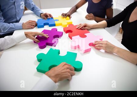 Hände von Geschäftsleuten Gebäude bunte Stichsäge Puzzles zusammen über Weiß Schreibtisch am Arbeitsplatz Stockfoto