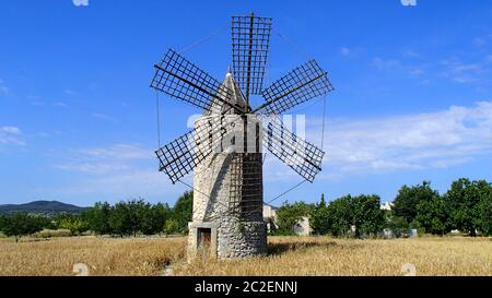 Typisch mallorquinische Windmühle auf ein Weizen auf die spanische Insel im Mittelmeer insel Mallorca und grüne Bäume vor blauem Himmel Stockfoto