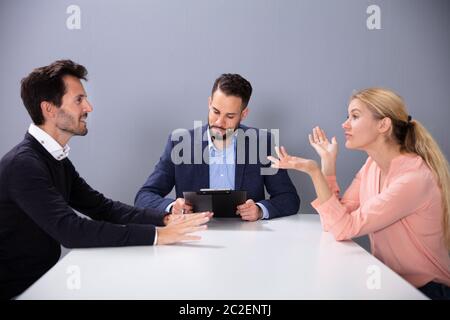 Unglücklich verheiratete Paar erhalten Geschiedene Streiten und Kämpfen Vor männlichen Rechtsanwalt im Büro Stockfoto