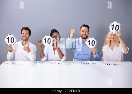 Panel von Angeregten Richter sitzen Vor dem grauen Wand mit 10 Score Cards Stockfoto