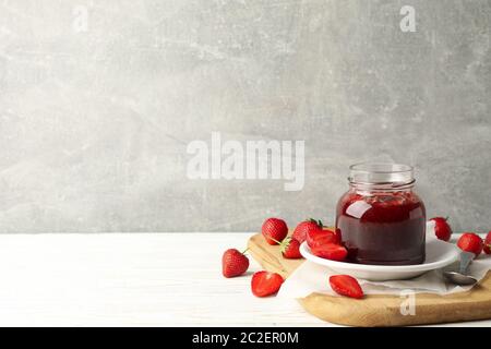 Komposition mit Erdbeermarmelade auf Holztisch vor grauem Hintergrund Stockfoto