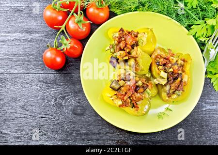 Paprika gefüllt mit Pilzen, Tomaten, Zucchini, Auberginen und Zwiebeln, mit Wein, Knoblauch, Thymian und Gewürze in einem grünen Platte gegen Bl gewürzt Stockfoto