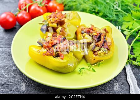 Paprika gefüllt mit Pilzen, Tomaten, Zucchini, Auberginen und Zwiebeln, mit Wein, Knoblauch, Thymian und Gewürze in einem grünen Platte gegen Bl gewürzt Stockfoto