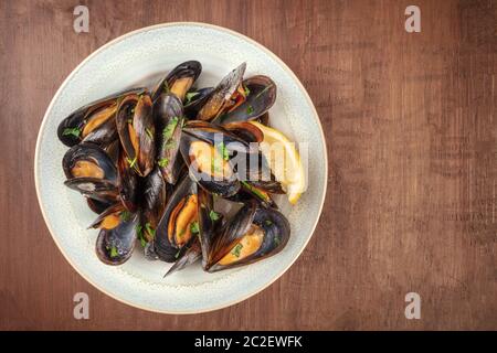 Marinara Muscheln, Moules Mariniere, Schuß von oben auf einen dunklen rustikalen Holztisch mit einem Platz für Text Stockfoto