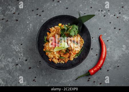 Thai Reis mit Huhn. Thai-Gericht mit Reis, Huhn, Jalta Zwiebel, Mais, Ananas, Tomaten, Sojasauce, Chili-Paste, Koriander, Limette, Chili-Pfeffer Stockfoto